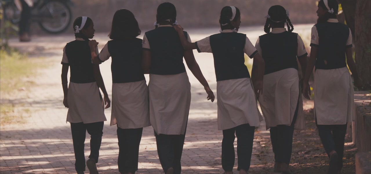 Schoolgirls walking away down a tree-lined path, Pune